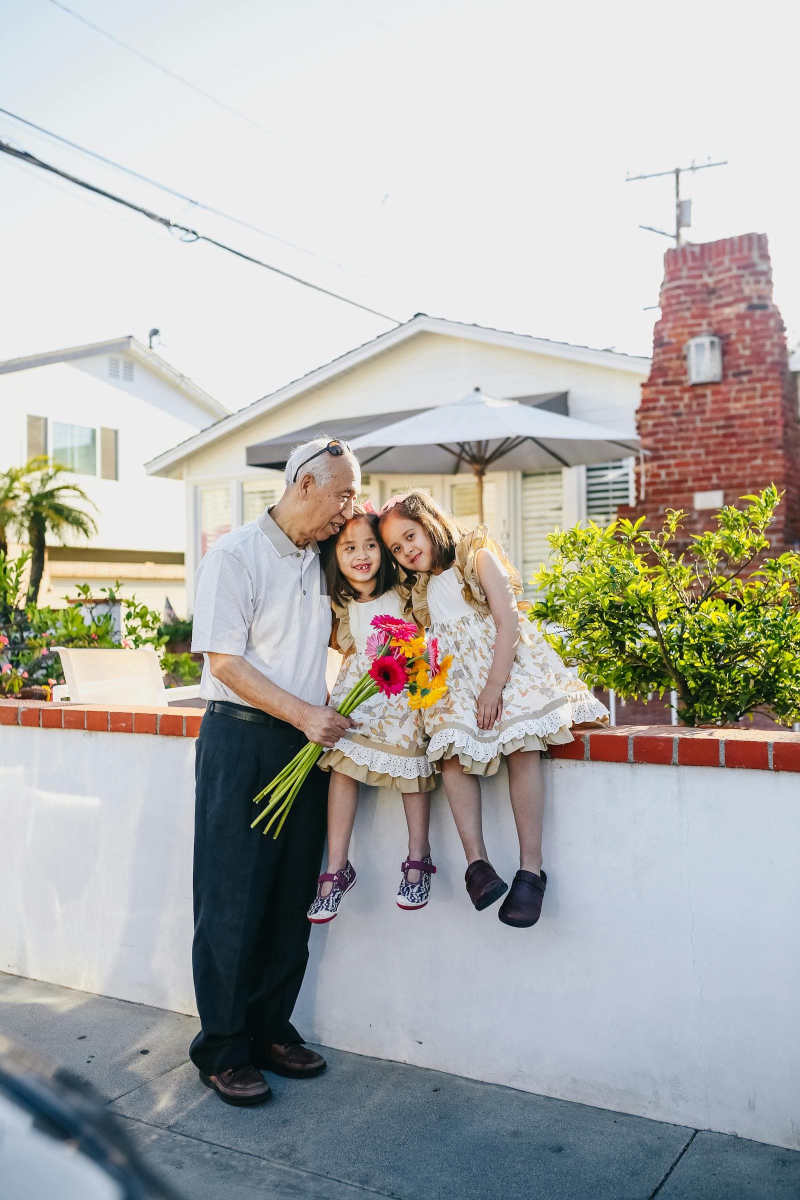 Abuelo abrazando a sus dos nietas en el patio de casa